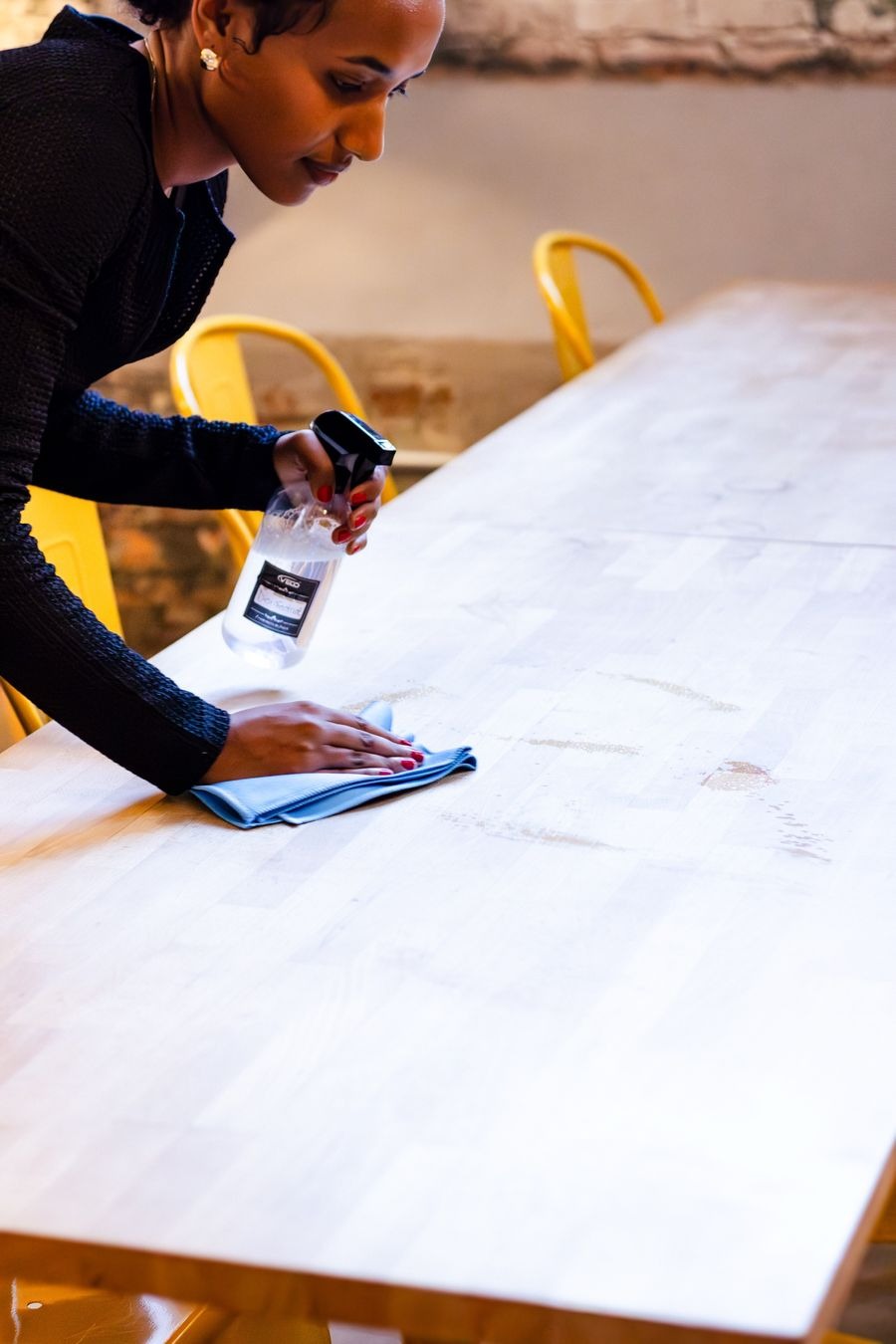 Spraying cleaner and wiping a table